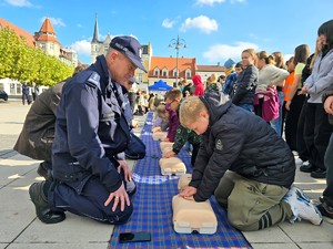 zdjęcie przedstawia: policjantów uczących dzieci reanimacji na manekinach.