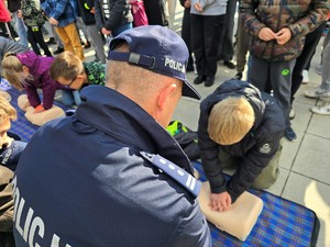 zdjęcie przedstawia: policjanta, który uczy nastolatka reanimacji.