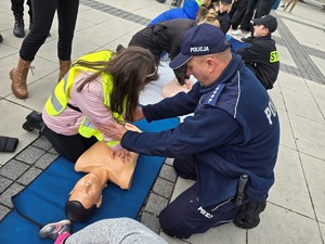 zdjęcie przedstawia: umundurowanego policja pomagającego w reanimacji na manekinie.