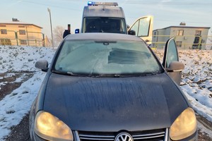 na zdjęciu zaparkowany pojazd z oblodzonymi szybami, a za nim policyjny radiowóz