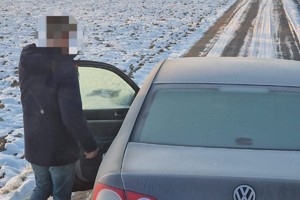 na zdjęciu osoba przy oblodzonym pojeździe na drodze