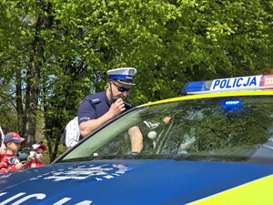 Zdjęcie przedstawia policjanta przy radiowozie.