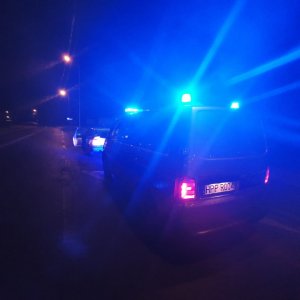 Policyjny radiowóz podczas zatrzymania samochodu osobowego do kontroli drogowej