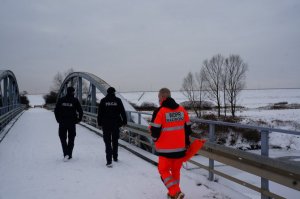 Policjanci wspólnie z ratownikiem wodnym na Płoni idą mostem