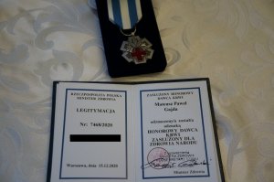 Medal i lkegitymacja Zasłuzony Dla Zdrowia Narodu, które otrzymał raciborski policjant