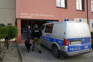 Policjant ze strażnikiem granicznym z psem słuzbowym obok radiowozu przy szkole w Rudniku