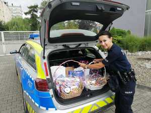 Policjantka wkłada słodycze do radiowozu