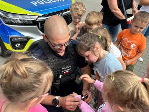 na zdjęciu policjant pokazuje kajdanki dzieciom