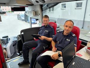 na zdjęciu 2 policjantów wypisuje ankietę w autobusie