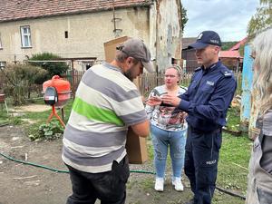 na zdjęciu komendant przekazuje szafę powodzianom