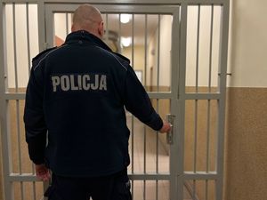 na zdjęciu policjant i kraty w pomieszczeniu zatrzymań