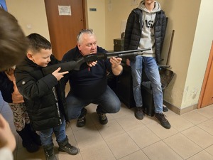 na zdjęciu policjant prezentuje gościom broń