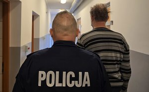 na zdjęciu policjant i zatrzymany stoją tyłem