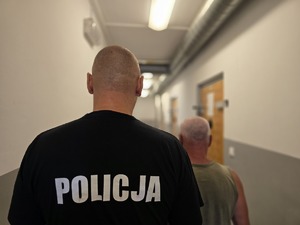 na zdjęciu mężczyzna z policjantem stoją tyłem