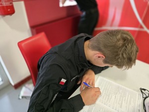 na zdjęciu uczeń klasy mundurowej wypełnia formularz