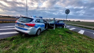 na zdjęciu pojazd audi i polcyjny radiowóz na pasie zieleni