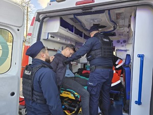 na zdjęciu widać jak policjant pomaga osobom poszkodowanym w wypadku