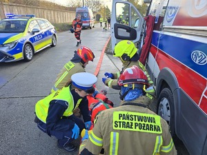 na zdjęciu widać jak policjant pomaga osobom poszkodowanym w wypadku