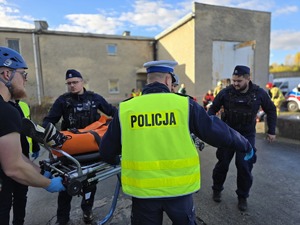 na zdjęciu widać jak policjant pomaga osobom poszkodowanym w wypadku