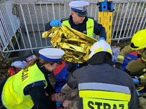 na zdjęciu policjanci pomagają osobie poszkodowanej