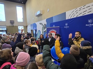 na zdjęciu stanowisko profilaktyczne dzieci przy nim a policjant i strażak rozmawiają o bezpieczeństwie