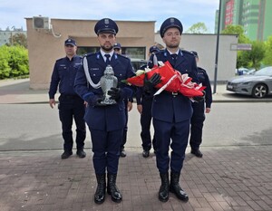 na zdjęciu policjanci z kwiatami oraz zniczem przed złożeniem pod obelisk