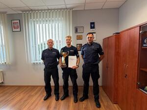 na zdjęciu komendant kierownik i policjant z pucharami