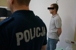 Policjant z zatrzymanym przed rejestracją daktyloskopijną