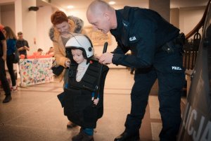 zdjęcie przedstawia policjanta w mundurze i chłopca ubranego w policyjne akcesoria