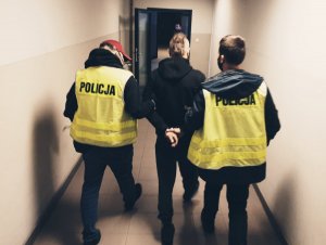 policjanci prowadzą zatrzymanego korytarzem