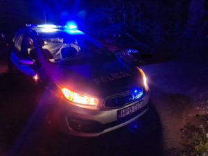 zdjęcie nocne policyjny radiowóz z włączonymi niebieskimi światłami