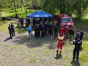 zdjęcie z drona - zbiórka policjantów i strażaków w terenie przed rozpoczęciem poszukiwań