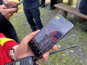 zdjęcie - strażak trzyma telefon z wyświetloną aplikacją i mapą