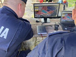 zdjęcie - sztab poszukiwań, dwaj policjanci patrzą na mapę wyświetloną na monitorze