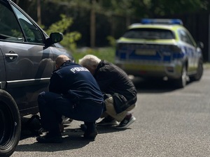 zdjęcie - policjant wymienia koło w samochodzie seniora, on obok, a w tle radiowóz