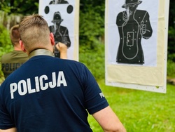 zdjęcie przedstawia zajęcia na strzelnicy otwartej podczas których policjant sprawdza wynik strzelania na tarczy