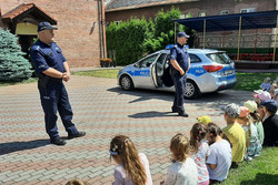 zdjęcie przedstawia plac przedszkolny, stojący policyjny radiowóz, dzieci i policjantów