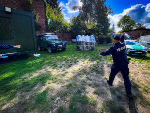 zdjęcie przedstawia szkolenie strażników granicznych - policjant rzuca w stojących z tarczami strażników butelkami z wodą