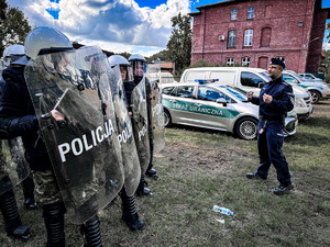 zdjęcie przedstawia szkolenie strażników granicznych - policjant stoi obok ustawionych w grupę strażników i objaśnia im zasady tworzenia szyku