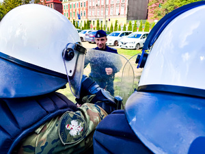 zdjęcie przedstawia szkolenie strażników granicznych - policjant widoczny z pomiędzy hełmów dwóch strażników granicznych