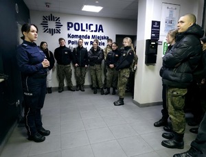 zdjęcie przedstawia uczniów klasy mundurowej witanych przez policjantkę w holu rudzkiej komendy