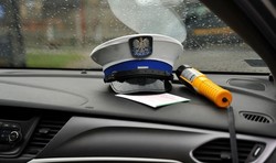 zdjęcie poglądowe przedstawia wnętrze radiowozu z leżącą czapką policjanta i alkotestem