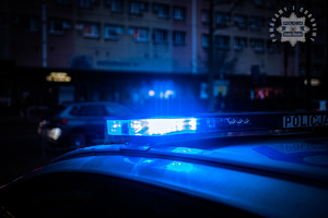 zdjęcie pokazuje policyjny radiowóz z włączonymi światłami błyskowymi