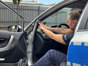 zdjęcie z treningu strzeleckiego pokazuje policjantkę za kierownicą radiowozu z otwartymi drzwiami i pistoletem w ręku