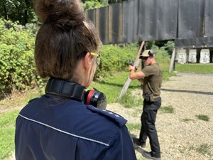 zdjęcie z treningu strzeleckiego pokazuje policjantkę obserwującą pokazującego zadanie do wykonania instruktora