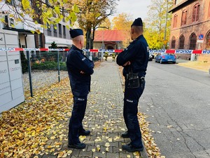 zdjęcie przedstawia dwóch policjantów pilnujących przejścia chodnikiem przy komisariacie