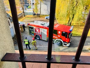 zdjęcie przedstawia widok z okna komisariatu na wóz straży pożarnej i ewakuowanych pracowników i polcijantów