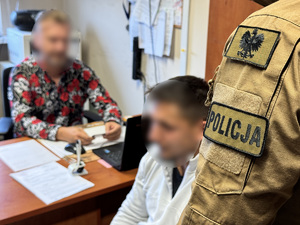 zdjęcie przedstawia policjantów w biurze razem z zatrzymanym