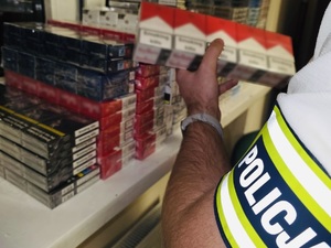 zdjęcie przedstawia policjanta trzymającego przechwycone paczki papierosów