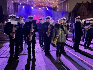 zdjęcie z koncertu policyjnej orkiestry na rudzkim jarmarku - policyjni muzycy i rudzianka śpiewająca kolendę